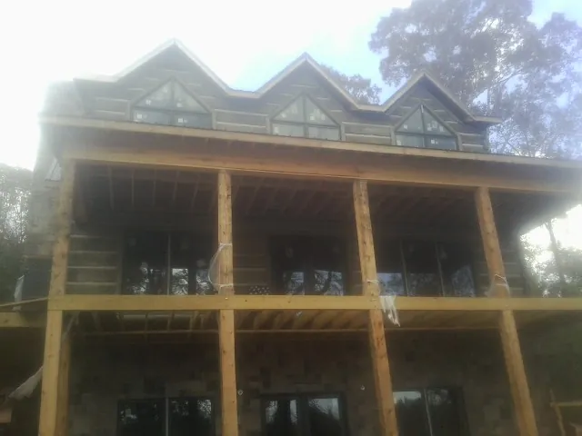 Dormers and porch framing on a large log home under construction — Roof Coating work by our crew in Springfield
